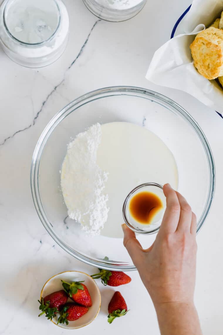 Vanilla Extract Being Added to a Bowl of Heavy Cream and Powdered Sugar