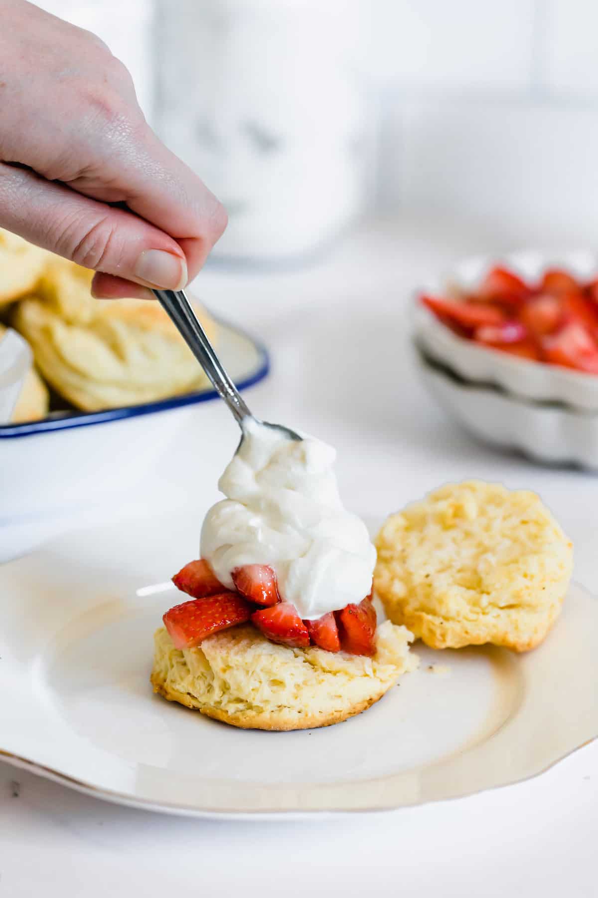 A Spoon Adding a Generous Dollop of Whipped Cream Over the Strawberry Filling on Half a Shortcake