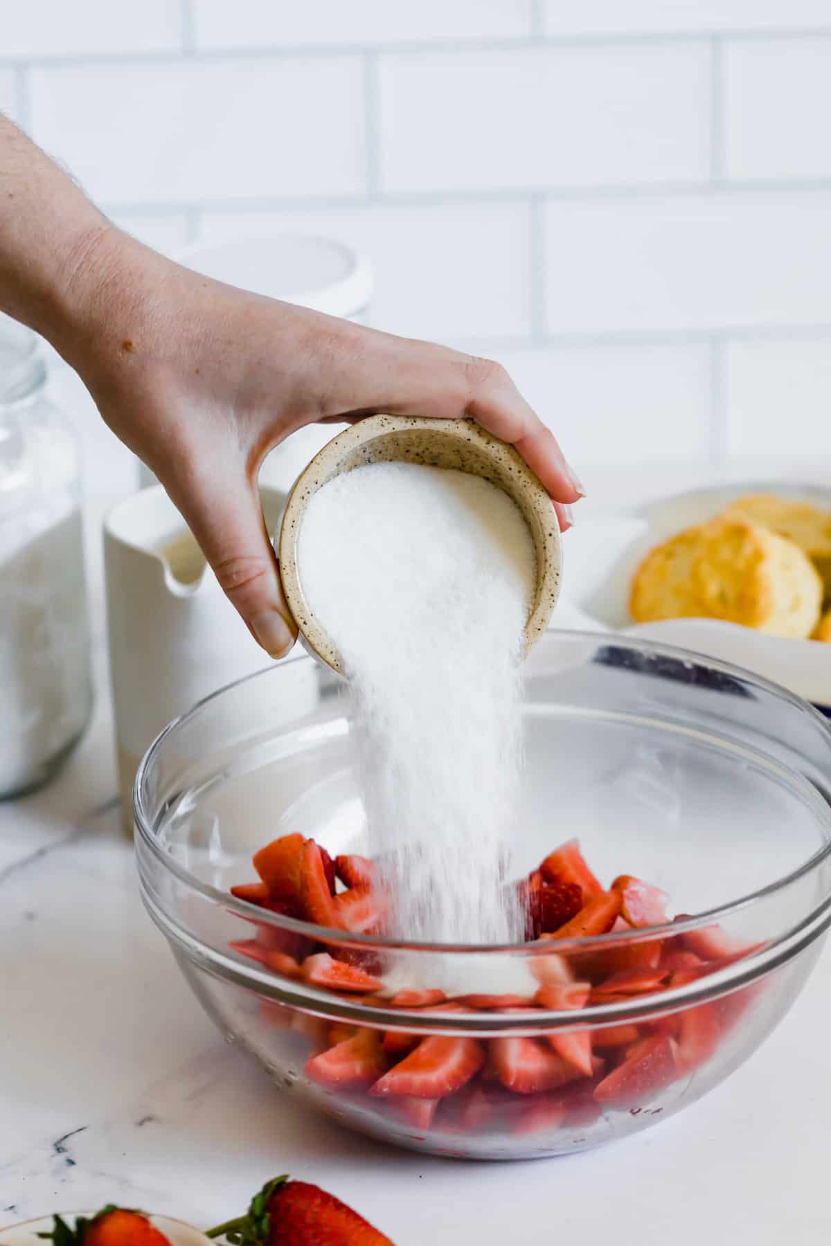 Sugar Being Poured Into a Bowl Containing Quartered Strawberries