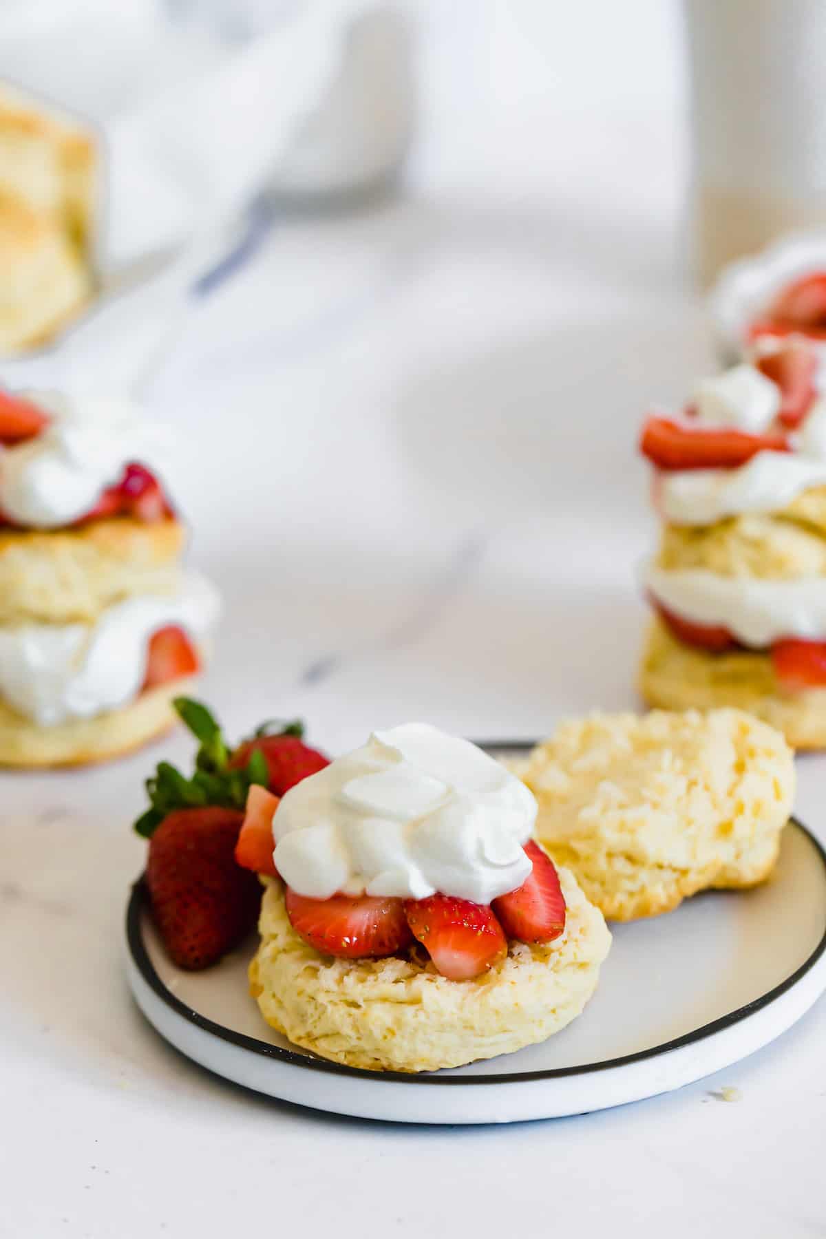 A Strawberry Shortcake on a Plate with the Top of the Biscuit and Fresh Strawberries on the Side