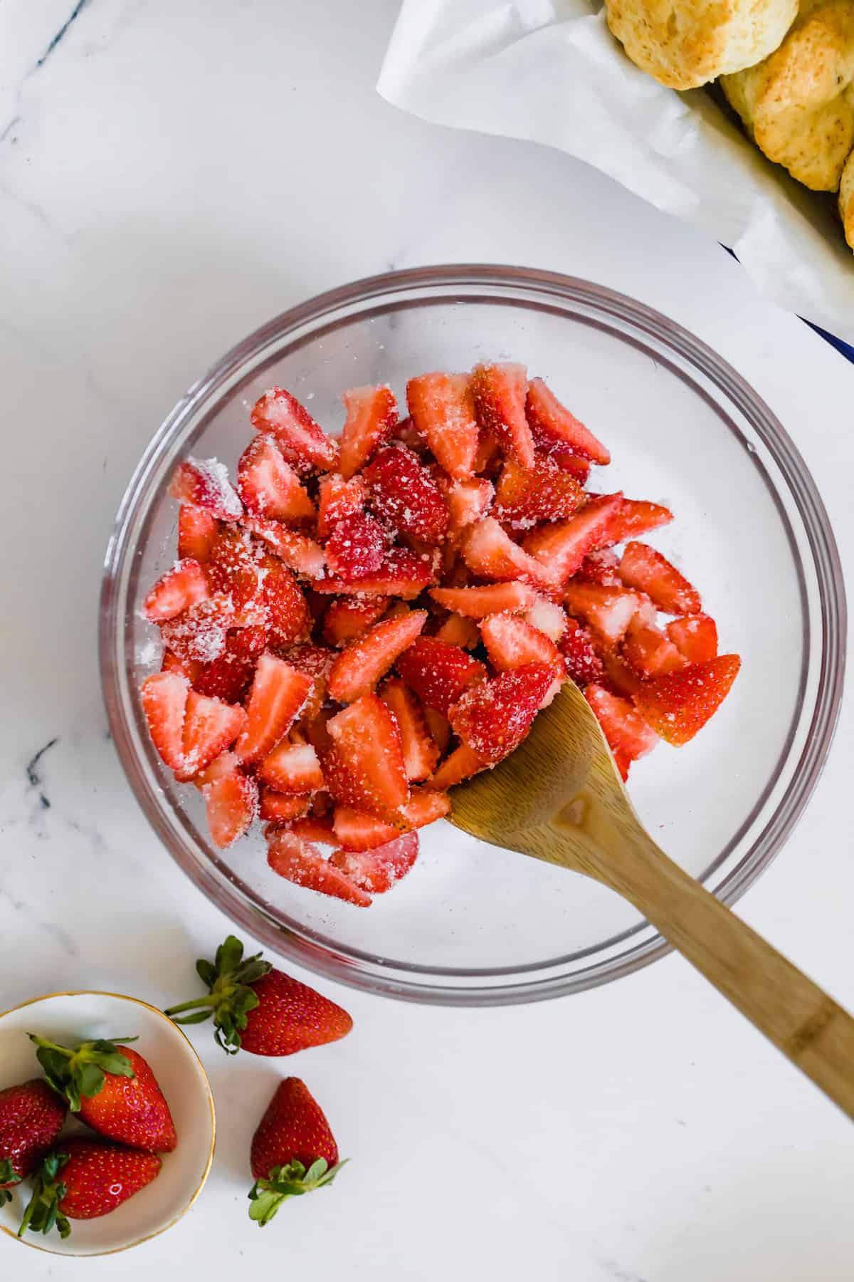 Strawberries in a Bowl with Sugar and a Wooden Spoon for Mixing