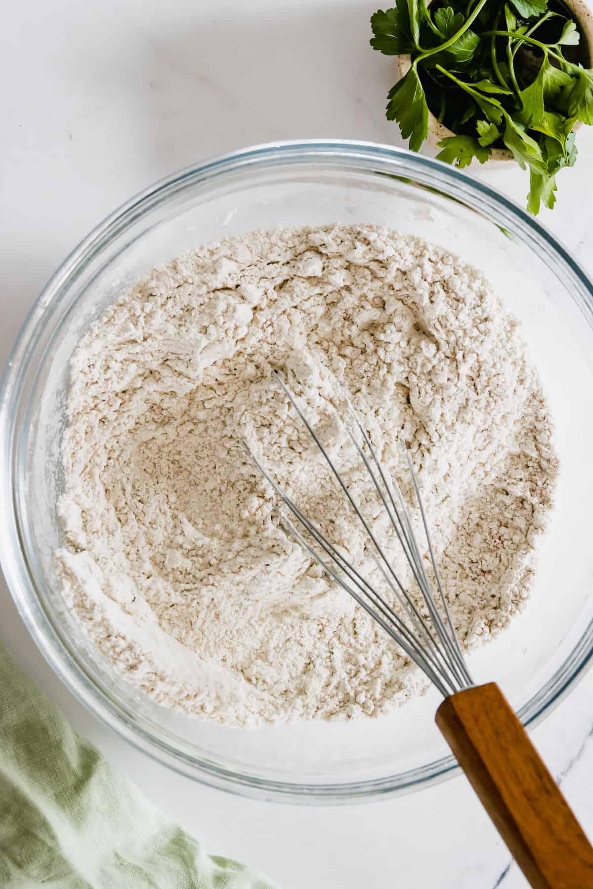 The Combined Dry Ingredients in a Bowl with a Whisk with a Wooden Handle