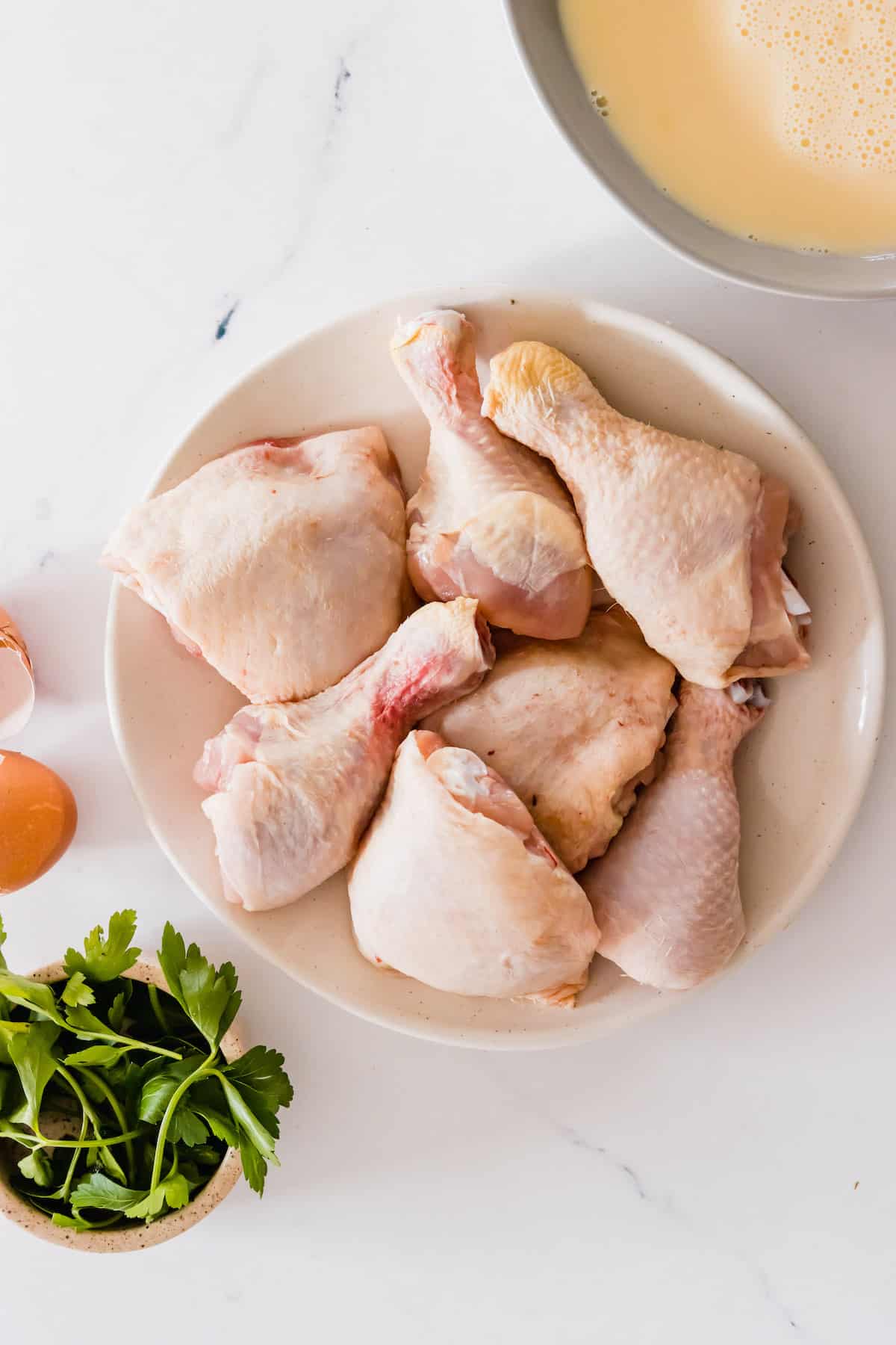 Seven Pieces of Raw, Skin-On Chicken on a White Plate
