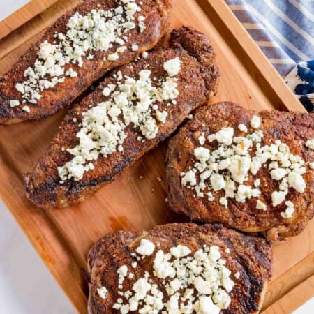 The Top View of Four Blackened Steaks Topped with Crumbled Blue Cheese