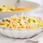 coleslaw in a small dish with a white napkin and the big serving bowl behind it