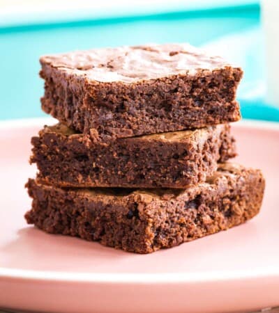 a stack of three fudgy gluten free brownies on a pale pink plate