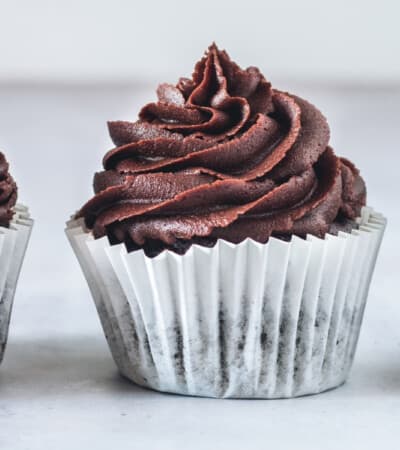 three chocolate cupcakes with chocolate frosting in a line