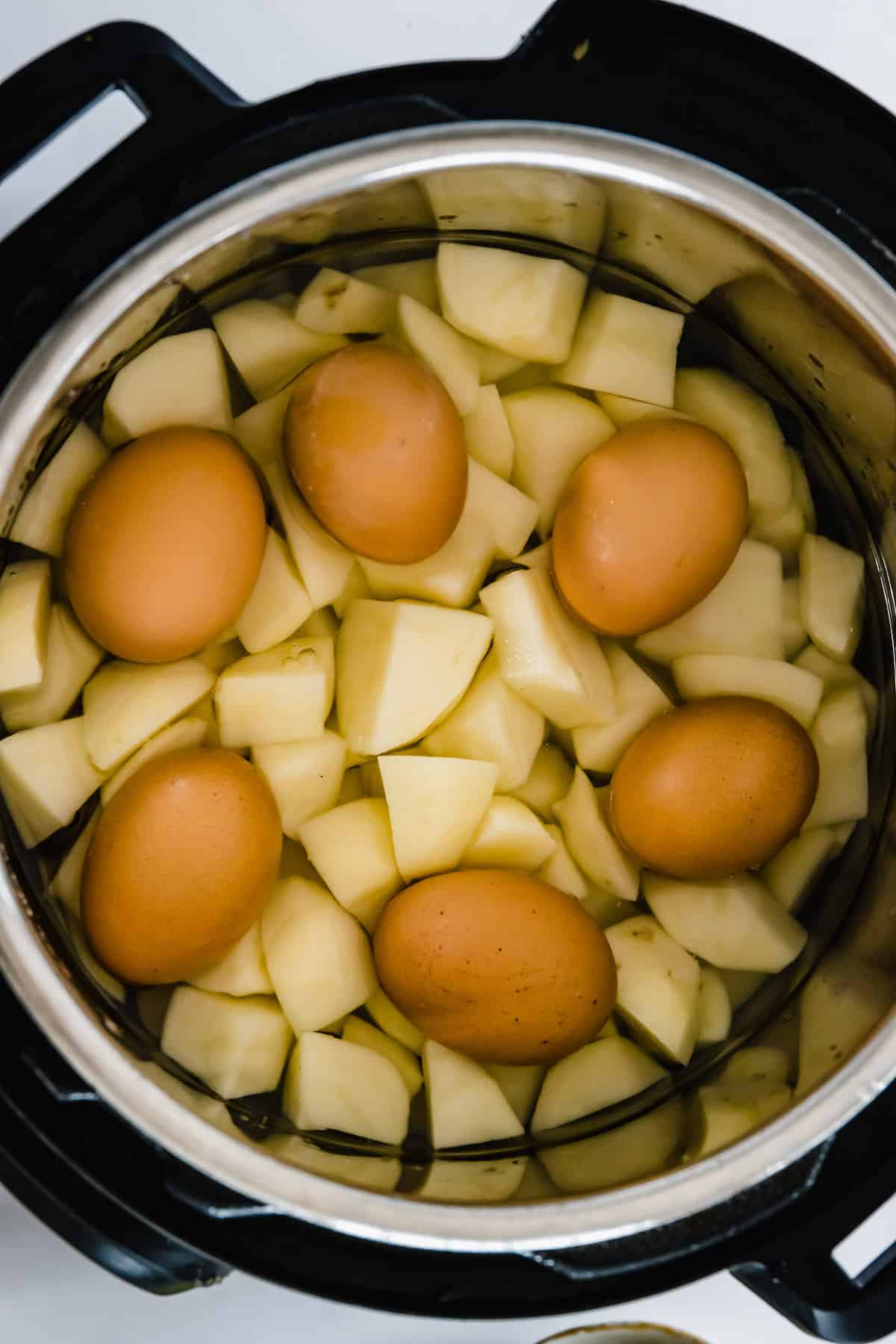 Peeled and Chopped Potatoes in an Instant Pot with Six Eggs on Top