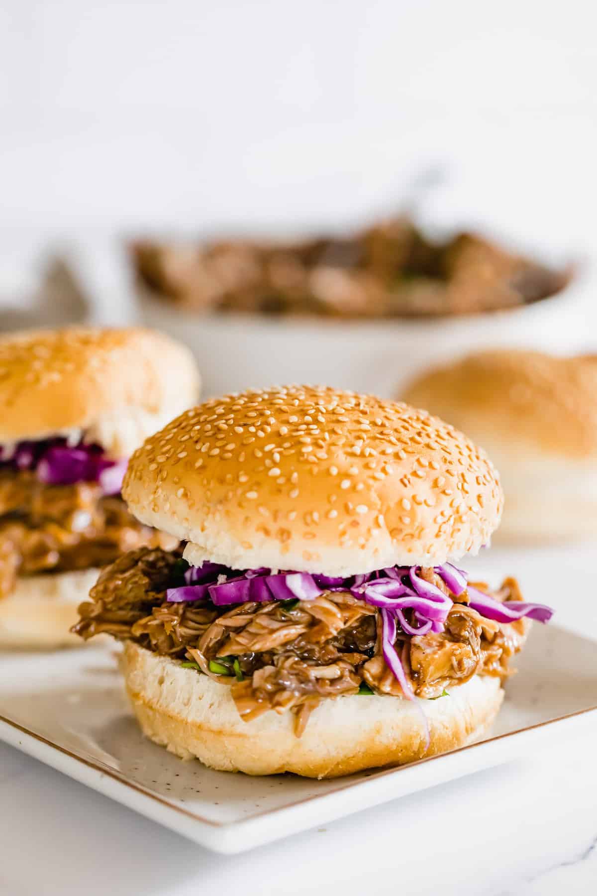 A Pulled Pork Sandwich with Onions on a White Serving Platter
