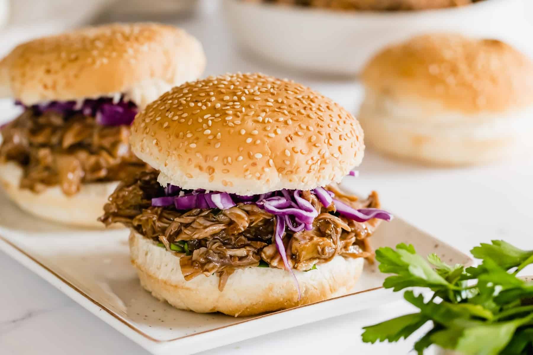 barbecue pulled pork sandwiches on sesame seed rolls.