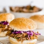 bbq pork sandwich on a sesame seed roll with a bit of red cabbage slaw