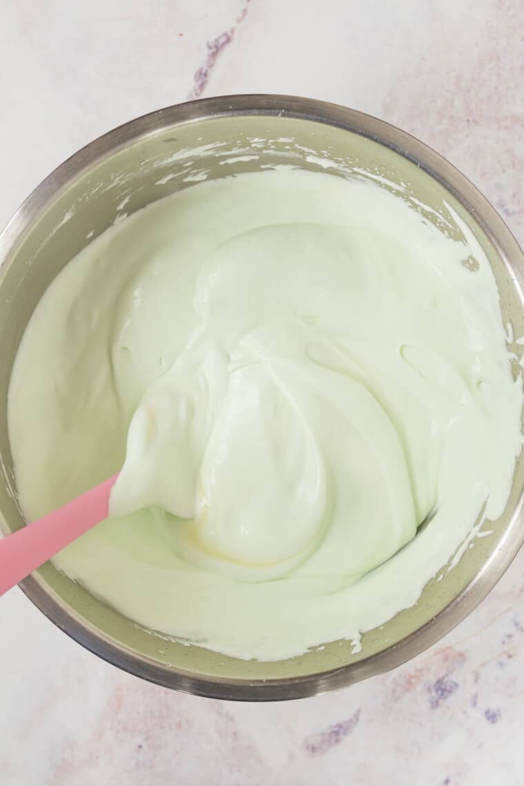 spatula folding the mint ice cream mixture in a bowl