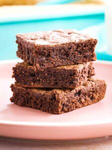 a stack of three fudgy gluten free brownies on a pale pink plate