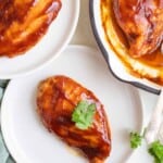two white plates each with a barbecue chicken breast with one more in a skillet