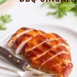 sliced barbecue chicken breast on a white plate with a fork and knife