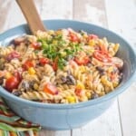 creamy southwestern pasta salad in a blue serving bowl on top of a multicolored striped napkin