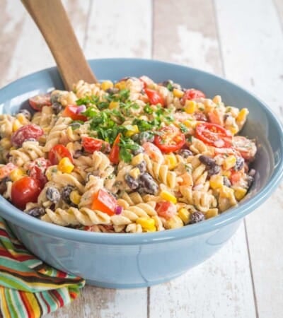 creamy southwestern pasta salad in a blue serving bowl on top of a multicolored striped napkin