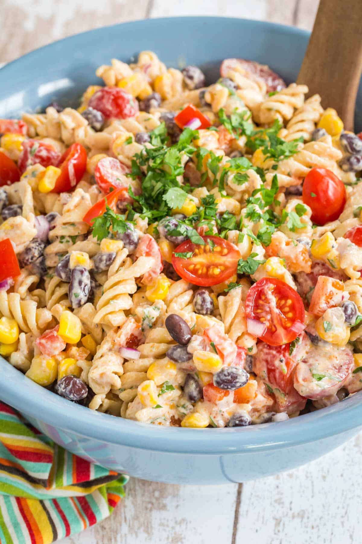 blue serving bowl of mexican pasta salad with creamy southwestern dressing with a wooden serving spoon