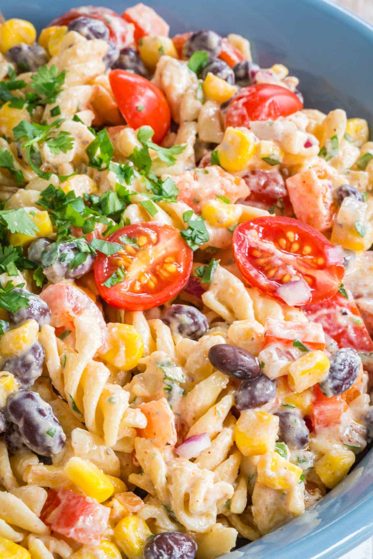 closeup of the rotini pasta, black beans, corn, peppers, tomatoes, and red onions coated in a creamy dressing with a garnish of cilantro