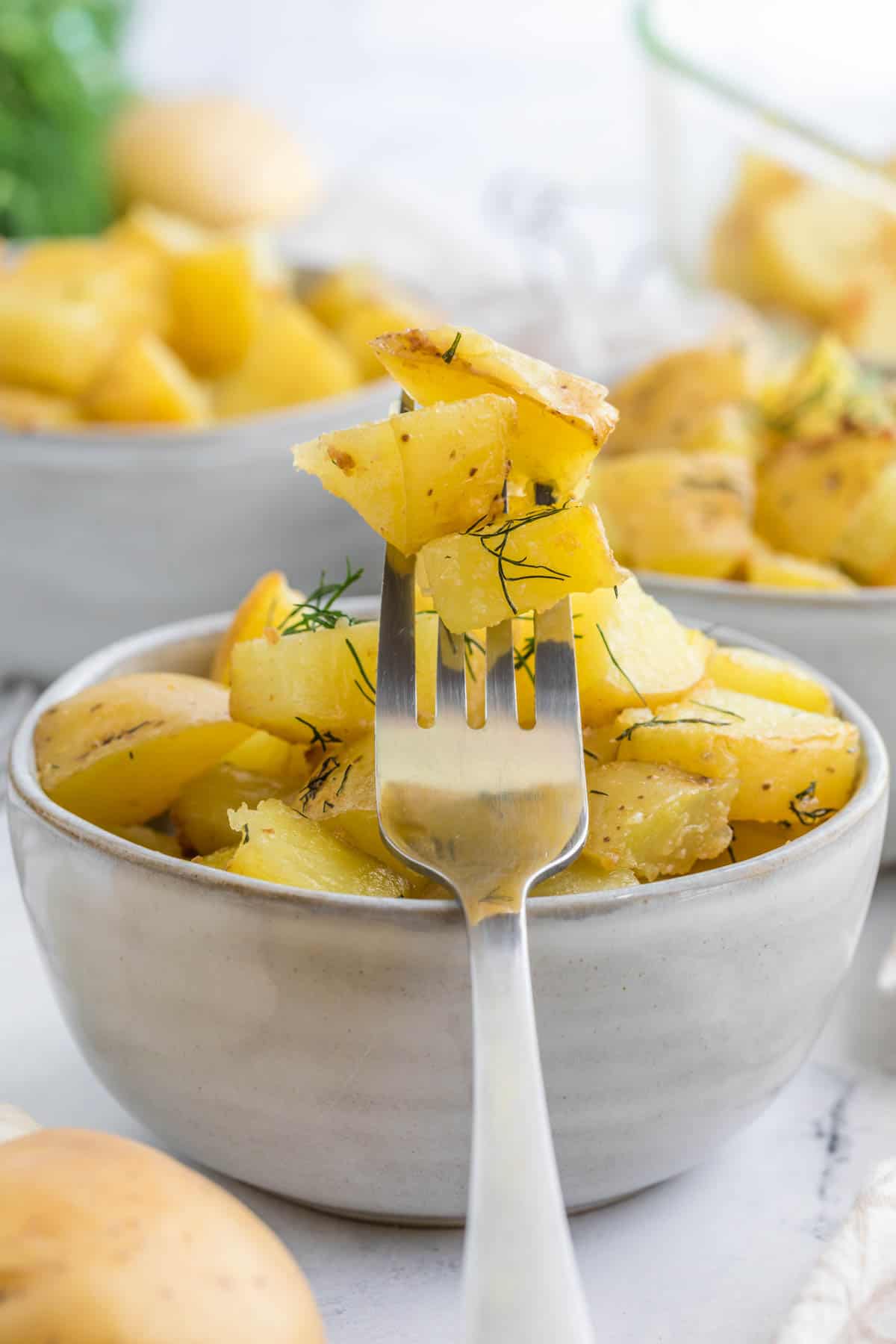 whtie bowl of crispy dill baked hash browns on a fork