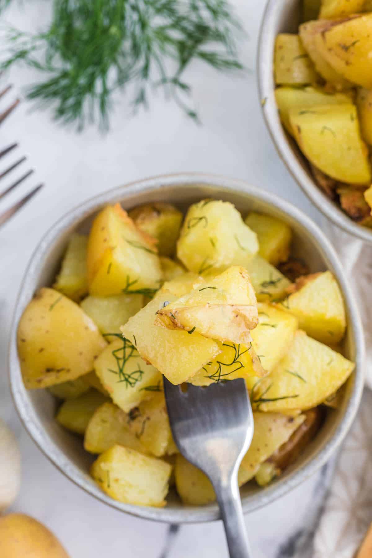 white bowl with dill hash brown potatoes and a fork