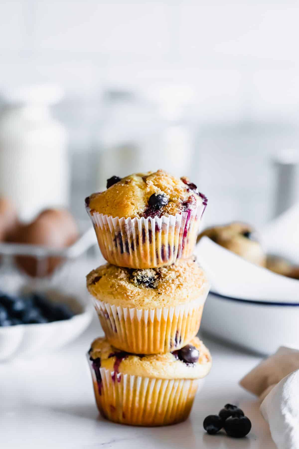 Three Blueberry Muffins Stacked on a White Marble Countertop