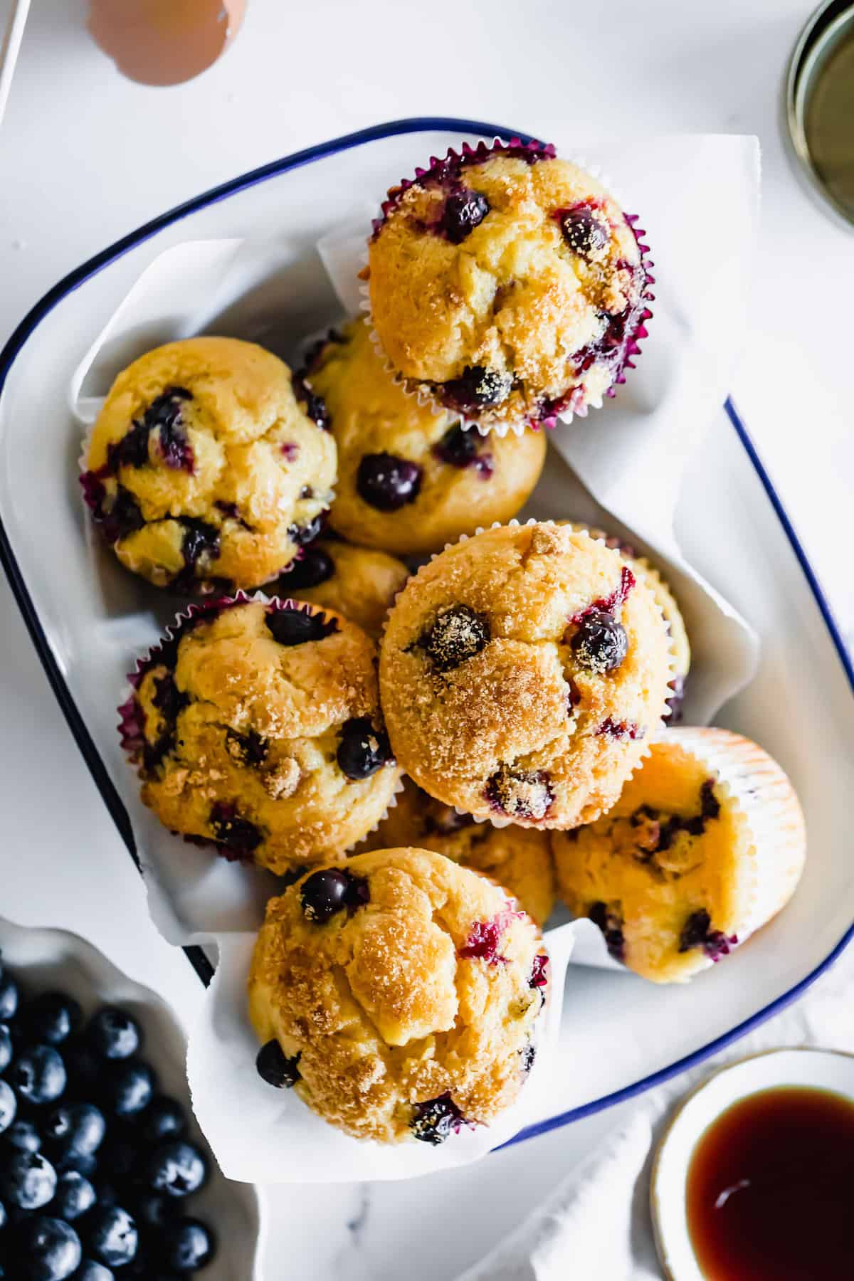 A Bird's-Eye View of a Dish of Blueberry Muffins on a Countertop with a Bowl of Fresh Berries