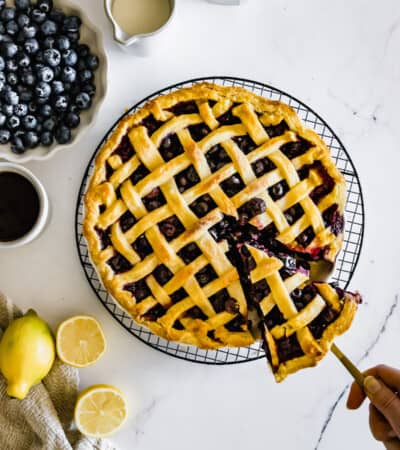 A Gluten-Free Blueberry Pie on a Wire Rack with One Slice Being Removed