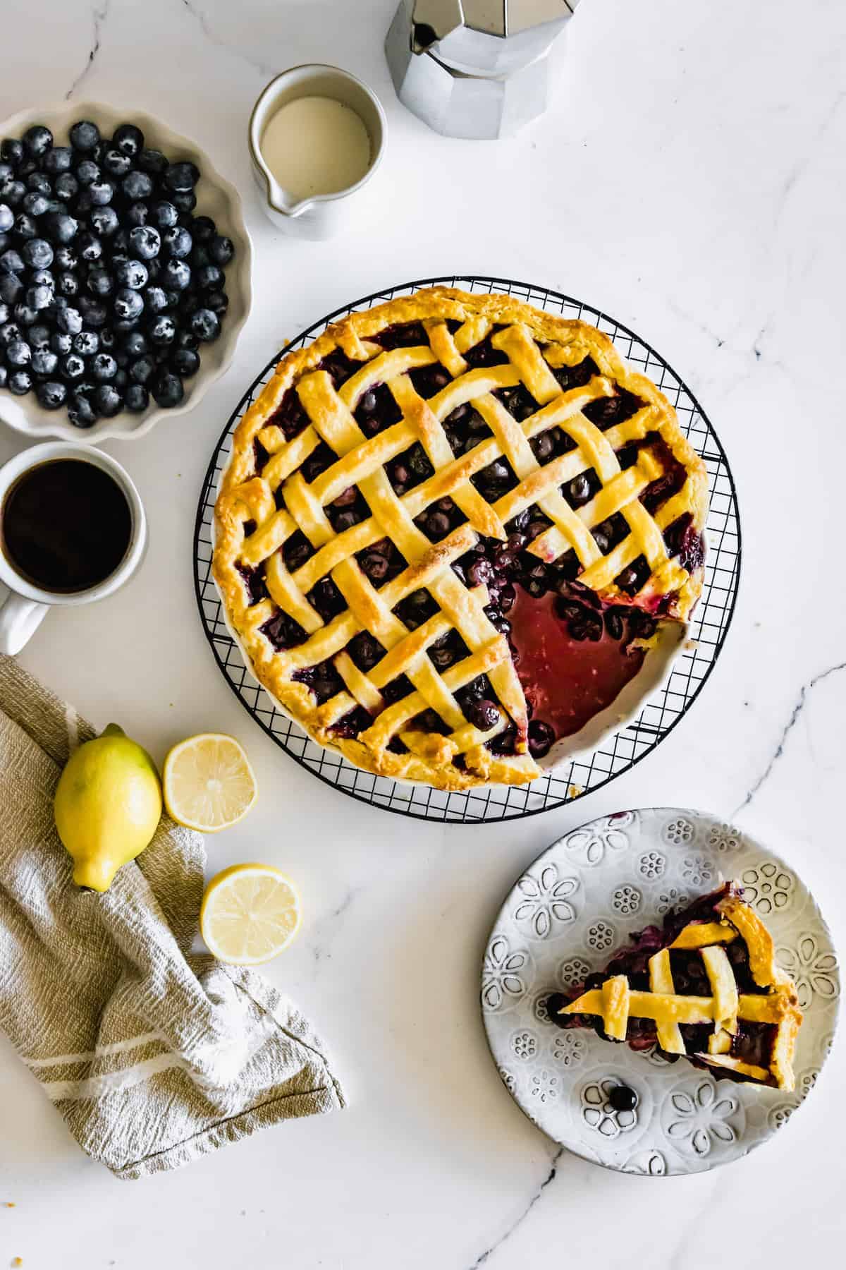 A Gluten-Free Blueberry Pie on a Metal Cooling Rack with One Piece on a Flowery Plate