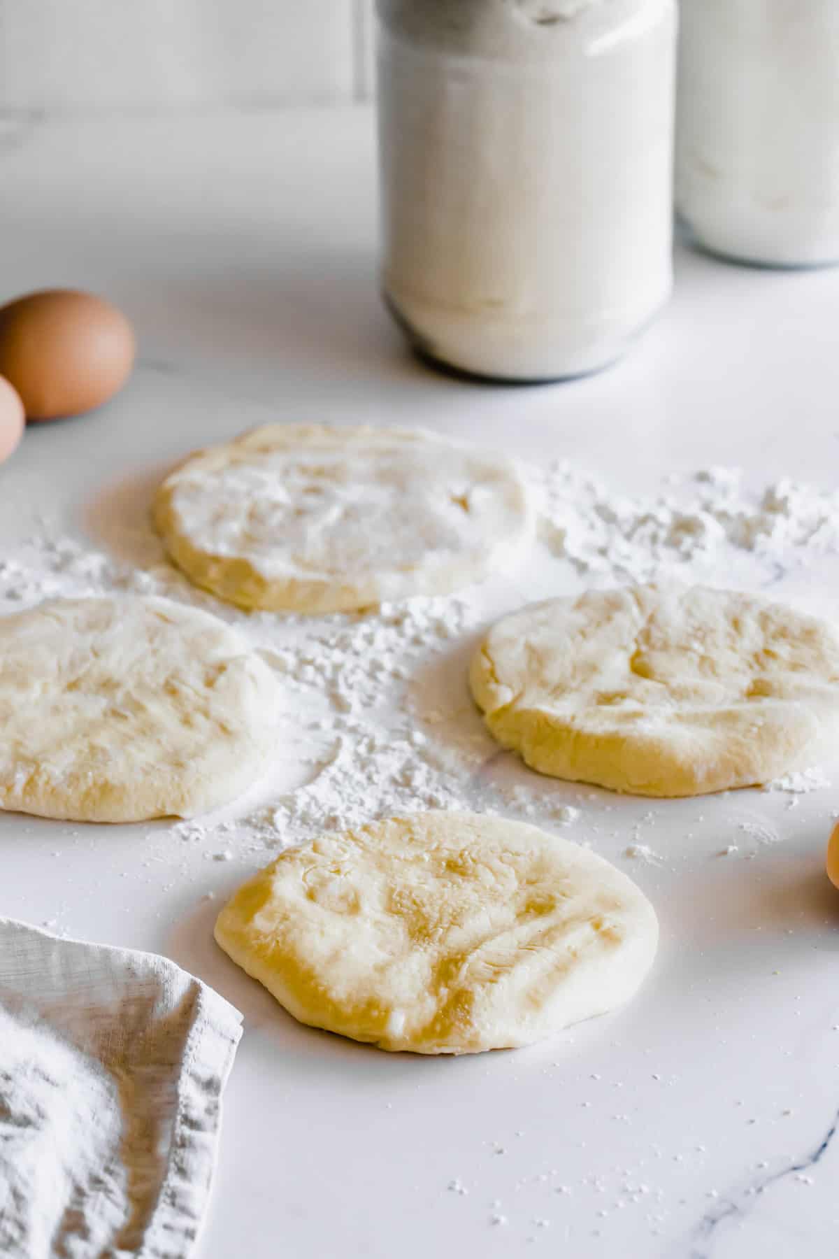 Four Discs of Gluten Free Pita Dough on a Well-Floured White Countertop