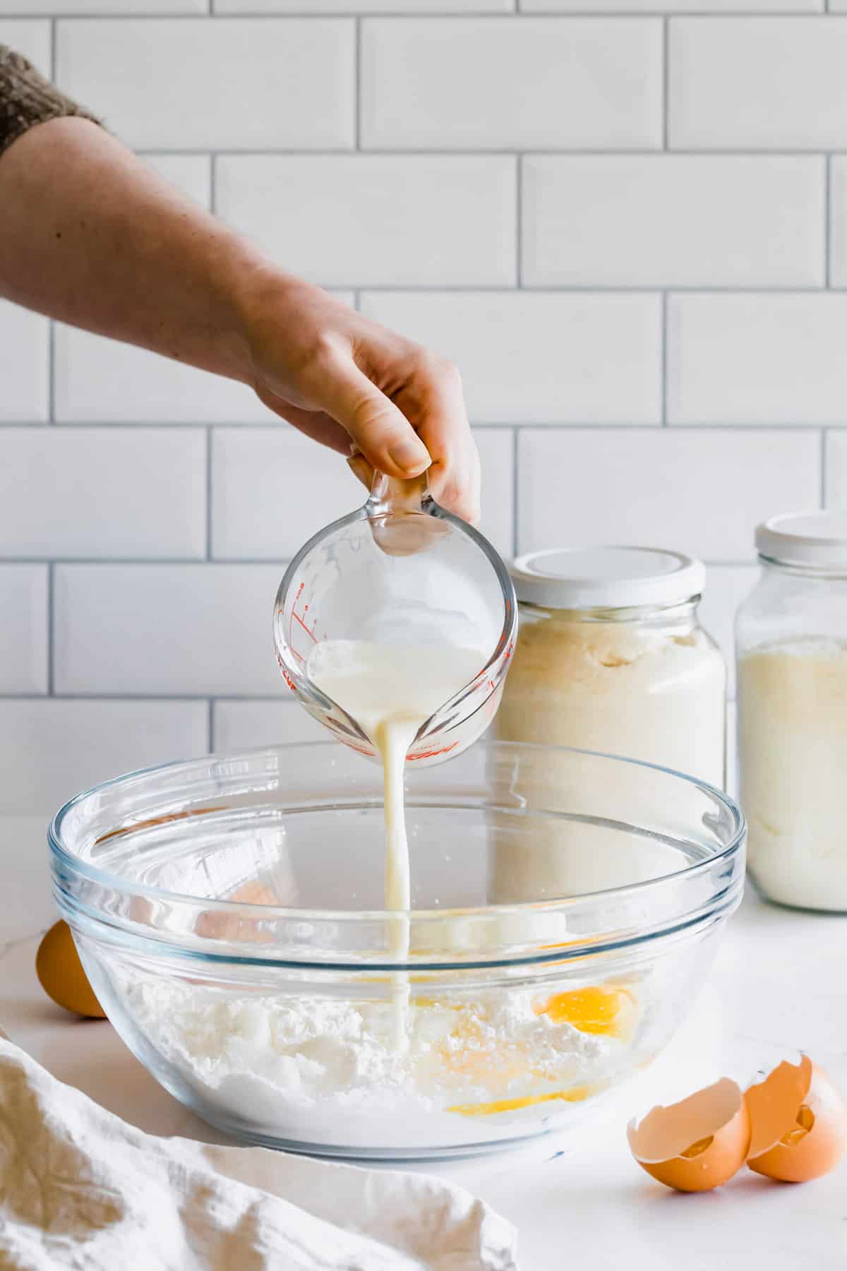 Milk Being Poured Into a Mixing Bowl with Eggs, Coconut Oil, Yogurt and the Dry Pita Ingredients