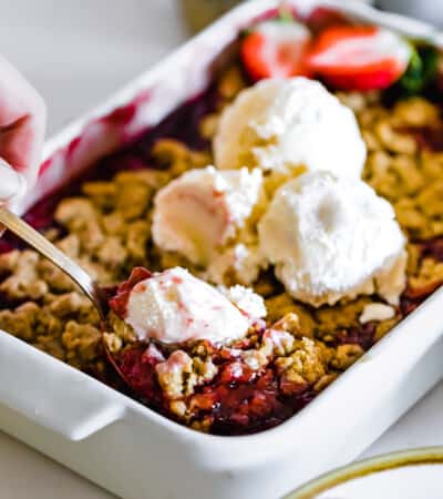 A Metal Spoon Being Dug Into a Fresh Pan of Strawberry Crumble