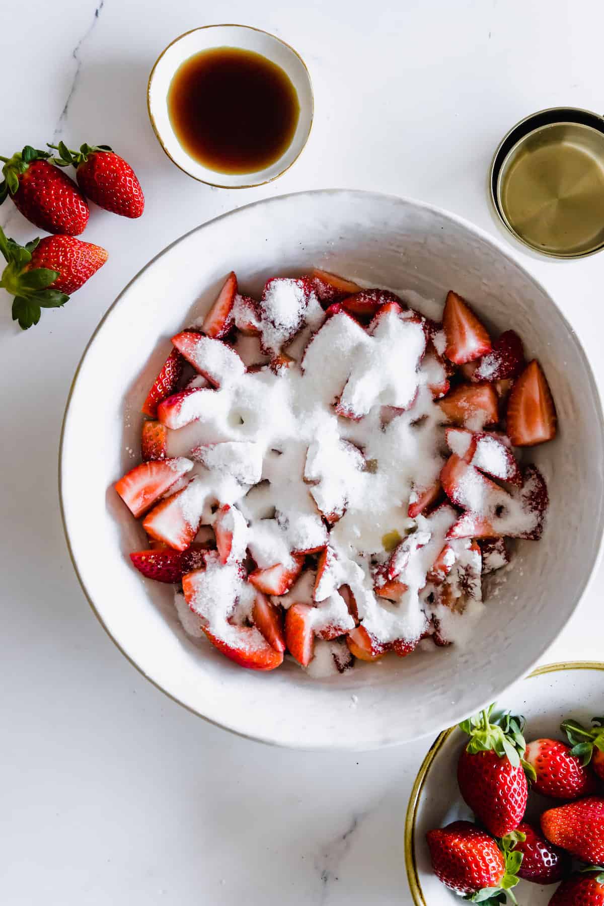 A bowl of quartered strawberries covered in granulated sugar.