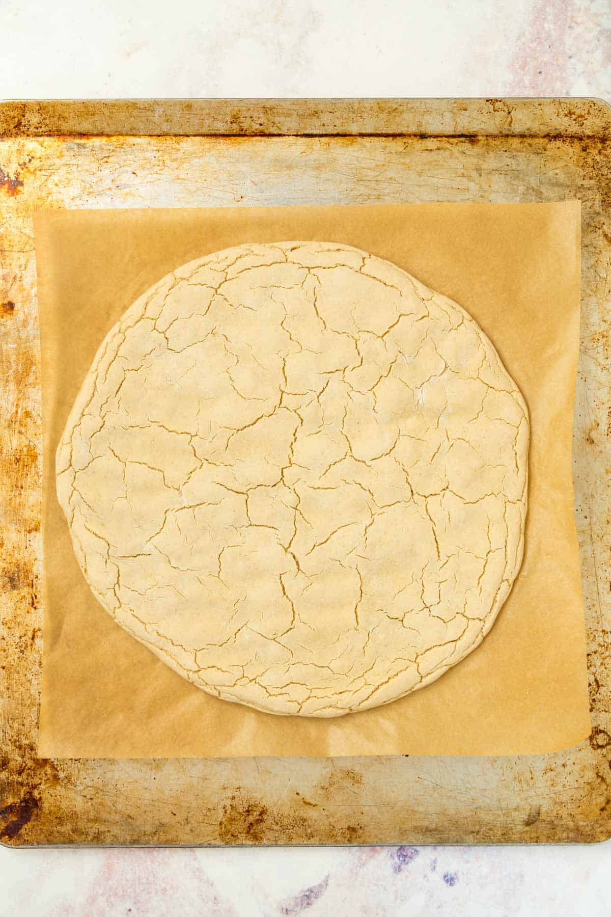 par-baked pizza crust on a parchment lined baking sheet