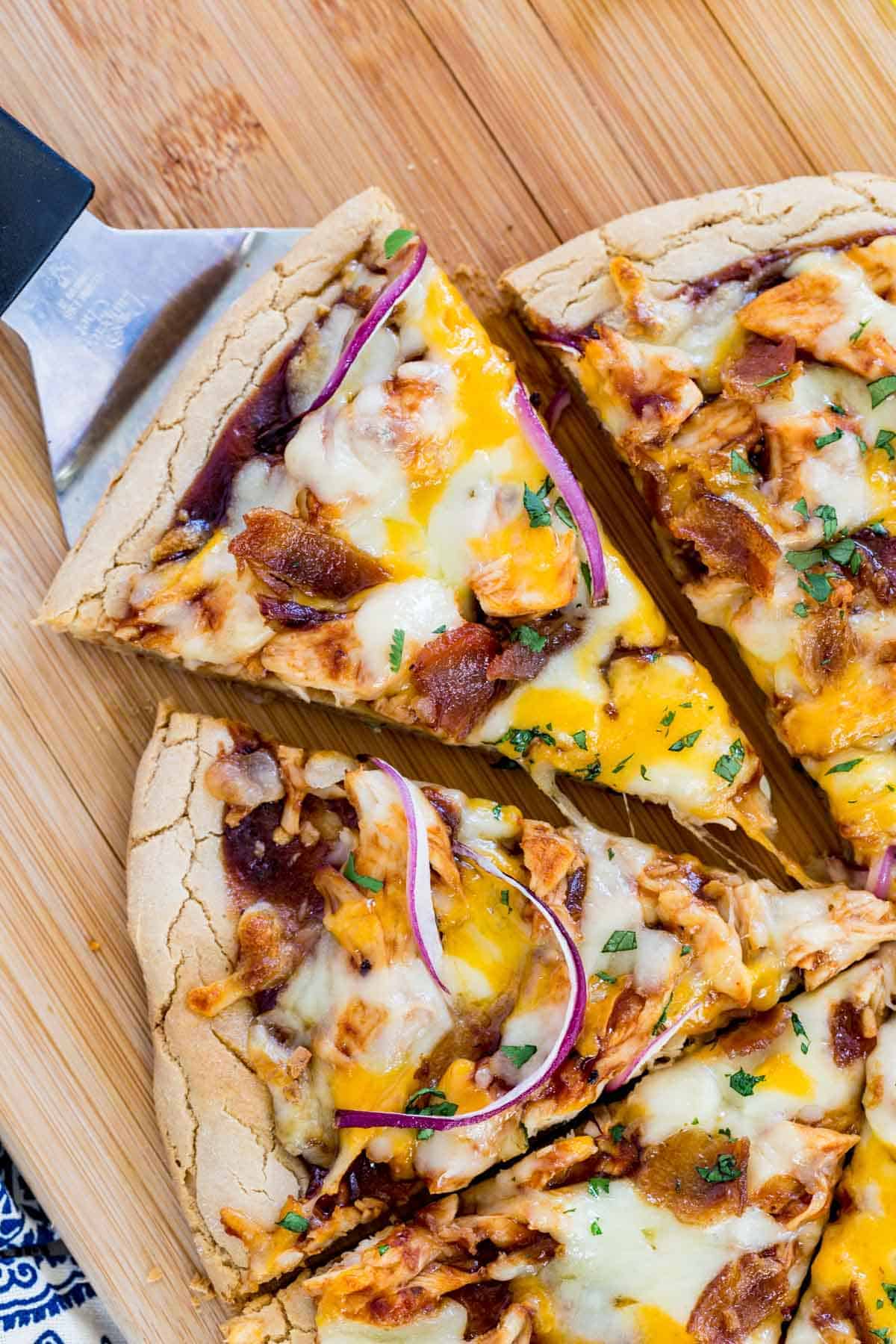 sliced bbq chicken pizza with a spatula pulling one piece away
