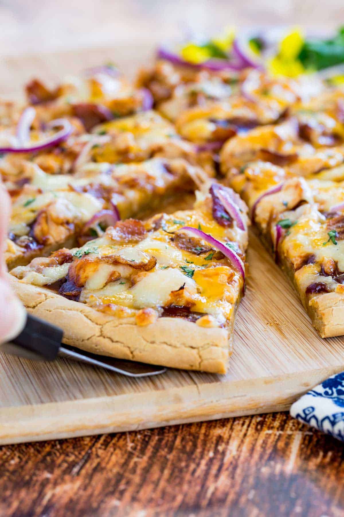 hand using a spatula to get a slice of pizza