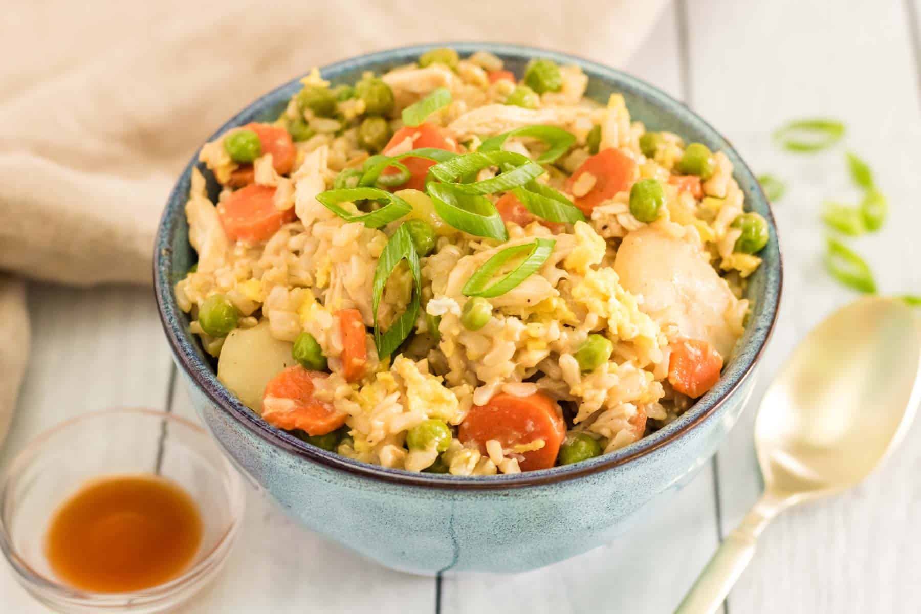 blue bowl with chicken fried rice topped with sliced scallions