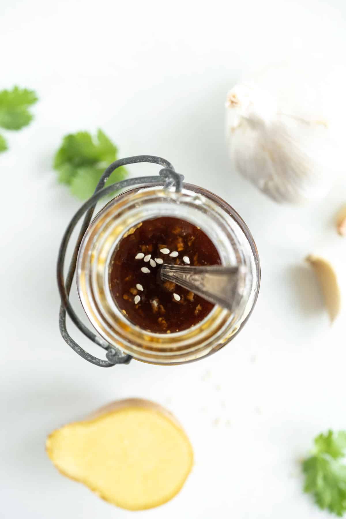 overhead of a glass jar with teriayki sauce topped with sesame seeds