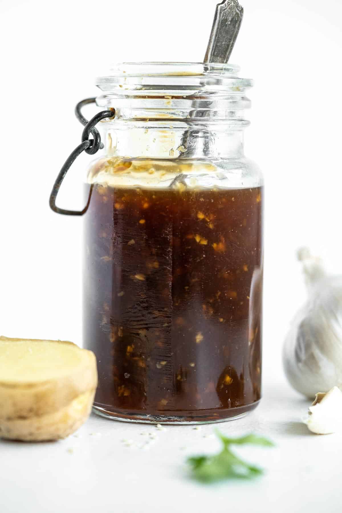 A bottle of teriyaki sauce with a spoon in it.
