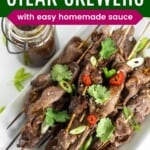 teriyaki steak skewers on a plattle sprinkled with cilantro, sesame seeds, chili pepper slices, and green onions