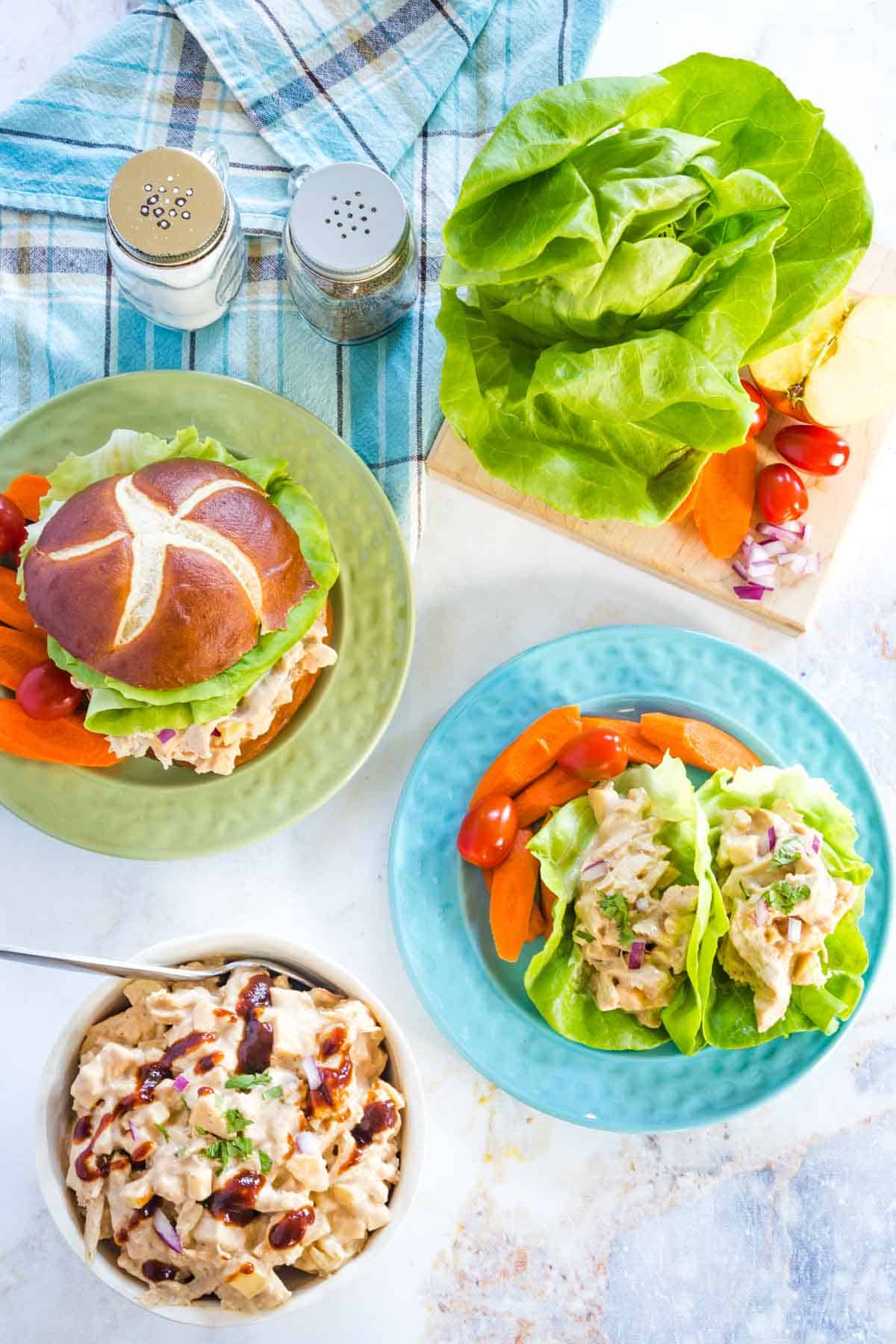 bbe chicken salad sandwich and lettuce wraps on plate with a bowl filled with more of the barbecue chicken salad, plus lettuce on a cutting board