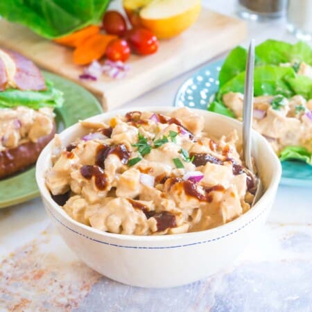 a bowl of bbq chicken salad in the middle with a sandwich on a plate to the left and lettuce wraps on a plate to the right