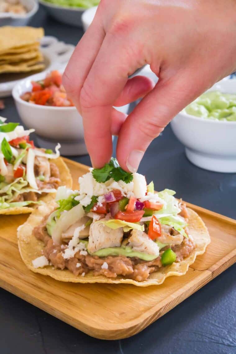 adding the cilantro garnish to the top of the finished chicken tostada