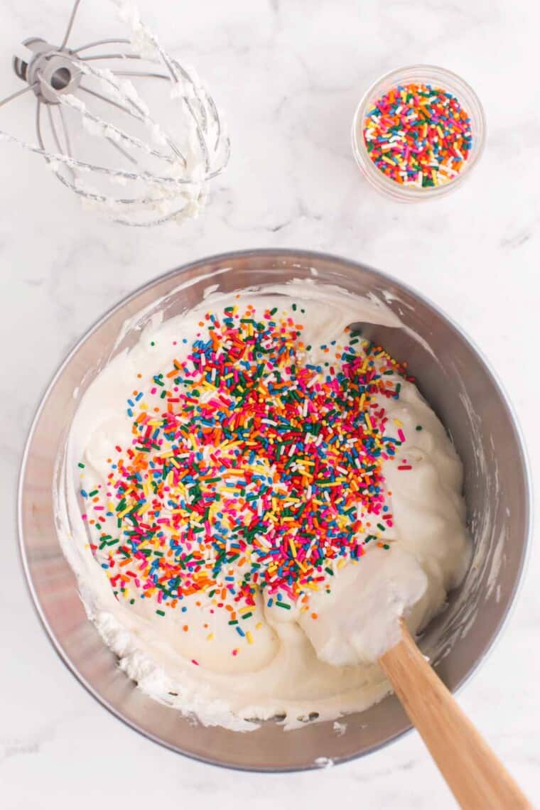 rainbow sprinkled poured on top of the ice cream base in a mixing bowl