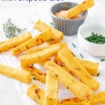 crispy polenta fries on a piece of parchment next to small bowls of a dipping sauce and minced chives
