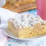one piece of gluten free crumb cake on a plate with a fork and a pink coffee mug
