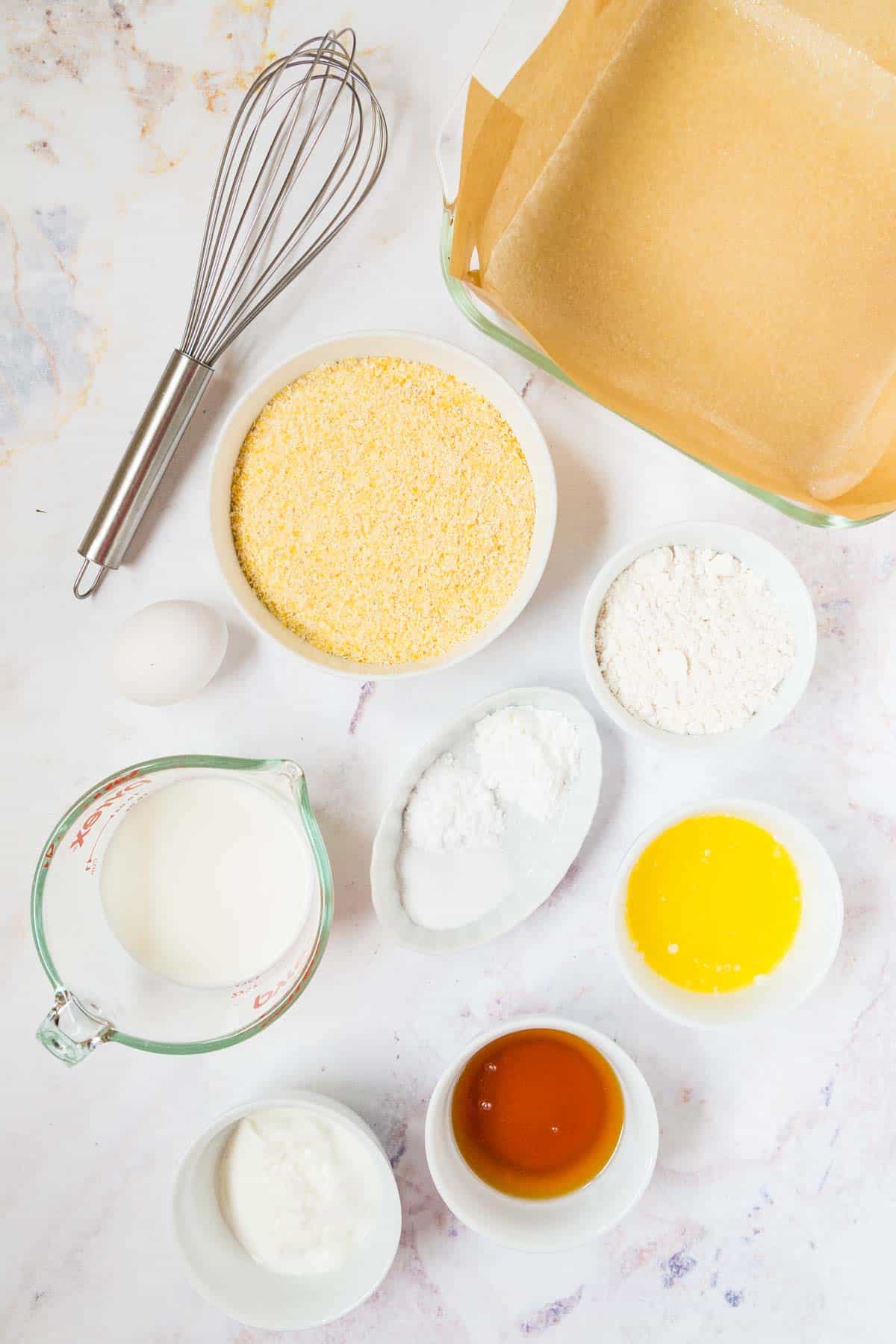 ingredients in small bowls with cornmeal, flour, honey, yogurt, and milk