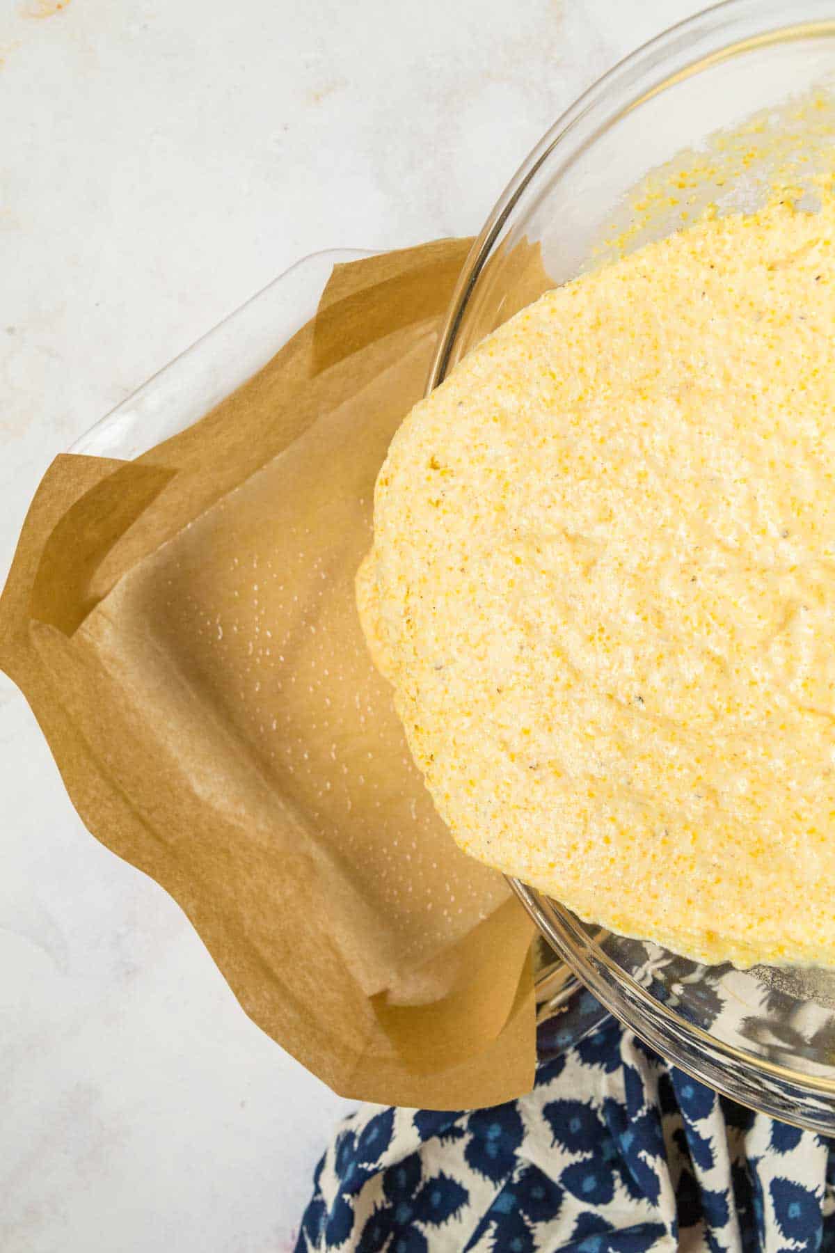 pouring cormeal batter into a baking dish lined with parchment paper