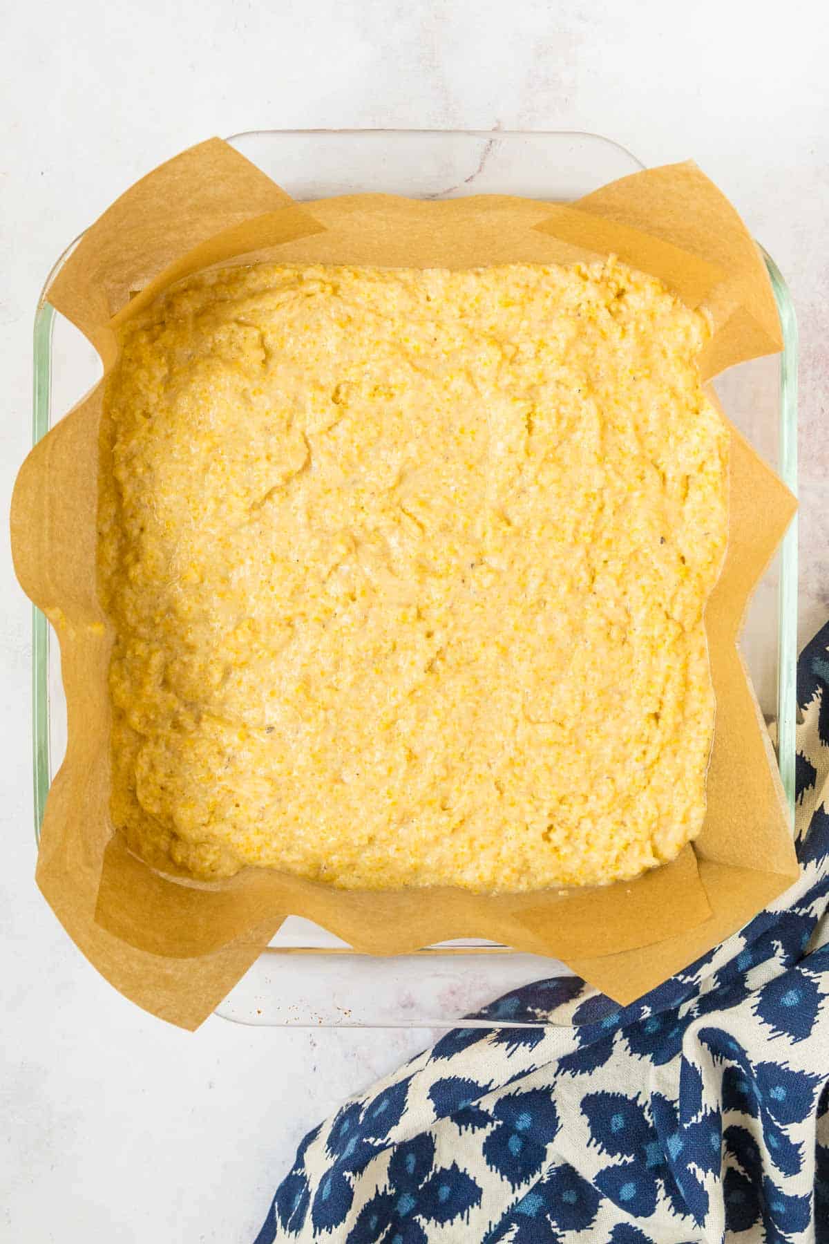 A lined baking pan filled with gluten-free cornbread batter.