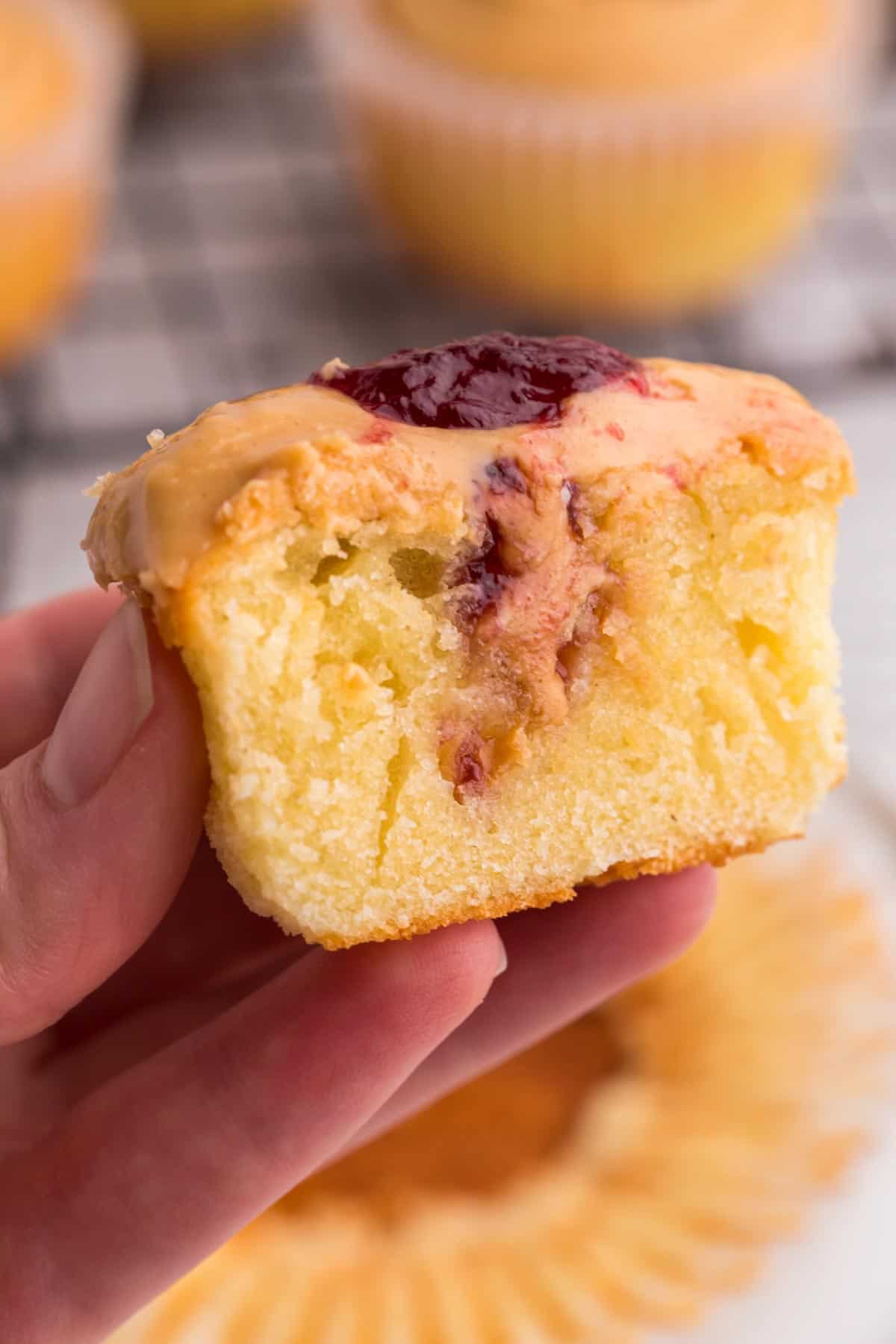 hand holding a cupcake cut in half to see the peanut butter and jelly filling